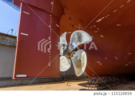Cargo vessel in dry dock on ship repairing yard. Variable pitch propeller and rudder. 115120659