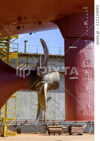 Cargo vessel in dry dock on ship repairing yard. Variable pitch propeller and rudder. 115120665