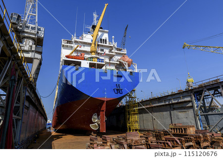 Cargo vessel in dry dock on ship repairing yard. Variable pitch propeller and rudder. 115120676