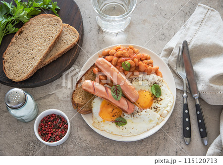 Traditional English breakfast with fried eggs, sausages, beans, fresh herb, red pepper and toast  115120713