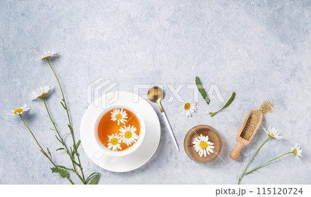 Healthy flat lay with chamomile tea in a white cup, vase, dry tea and  flowers daisy  115120724