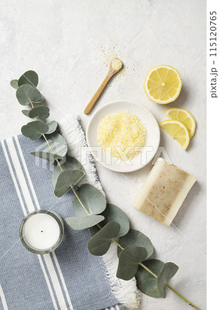 Organic yellow sea salt with lemon, soap and eucalyptus branch on a white textured background.  115120765