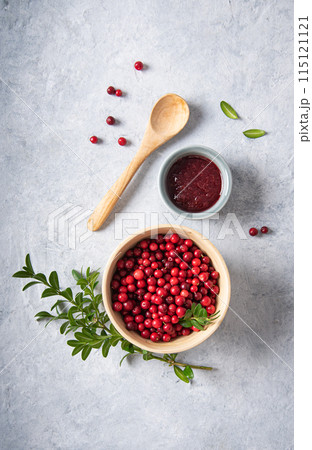 juicy forest lingonberry with handmade jam in a wooden bowl on white table. juicy forest lingonberry with handmade jam in a wooden bowl on white table. 115121121