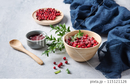 juicy forest lingonberry with handmade jam in a wooden bowl on white table with blue napkin.  115121126