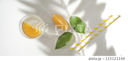 A glass of mineral water and a slice of orange on a light table with fresh juicy fruit oranges A glass of mineral water and a slice of orange on a light table with fresh juicy fruit oranges 115121148