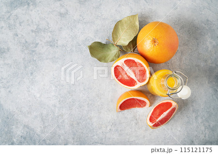 layout of juicy red grapefruits and juice in a bottle on a blue background. layout of juicy red grapefruits and juice in a bottle on a blue background. 115121175