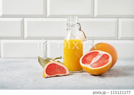 juicy grapefruit and bottle juice on a blue table on a white brick background. Front view juicy grapefruit and bottle juice on a blue table on a white brick background. Front view 115121177
