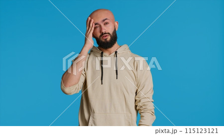 Muslim man suffering from serious migraine on camera, trying to rub temples to ease the pressure. Young middle eastern adult feeling unwell with painful headache, sick person. Camera 1. Muslim man suffering from serious migraine on camera, trying to rub temples to ease the pressure. Young middle eastern adult feeling unwell with painful headache, sick person. Camera 1. 115123121