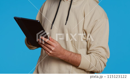 Arab guy using tablet to scroll on online websites, looking for something on the internet and using social media apps. Modern person working with touchscreen device in studio. Camera 2. Arab guy using tablet to scroll on online websites, looking for something on the internet and using social media apps. Modern person working with touchscreen device in studio. Camera 2. 115123122