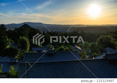 古都奈良東大寺二月堂からの夕景　東大寺境内から大仏殿の屋根越しの夕焼け色に染まり始めた生駒山上の空③ 115123407