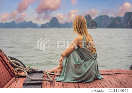 Attractive woman in a dress is traveling by boat in Halong Bay. Vietnam. Travel to Asia, happiness emotion, summer holiday concept. Picturesque sea landscape. Ha Long Bay, Vietnam Attractive woman in a dress is traveling by boat in Halong Bay. Vietnam. Travel to Asia, happiness emotion, summer holiday concept. Picturesque sea landscape. Ha Long Bay, Vietnam 115124045