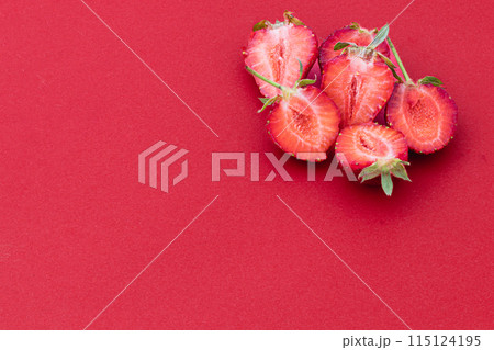 Cut and whole ripe strawberries on a red background 115124195