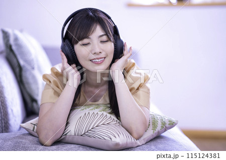 ソファに寝転んで音楽を聴く女性 ソファに寝転んで音楽を聴く女性 115124381