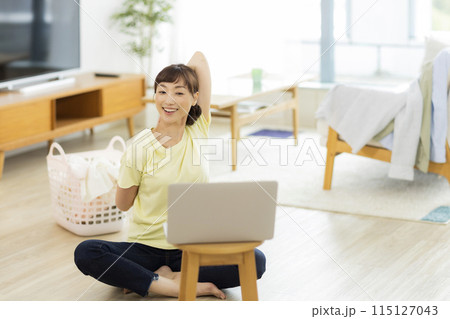 パソコンを見ながらストレッチをする女性 　 115127043