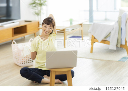 パソコンを見ながらストレッチをする女性 パソコンを見ながらストレッチをする女性 115127045