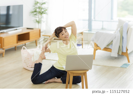 パソコンを見ながらストレッチをする女性 パソコンを見ながらストレッチをする女性 115127052
