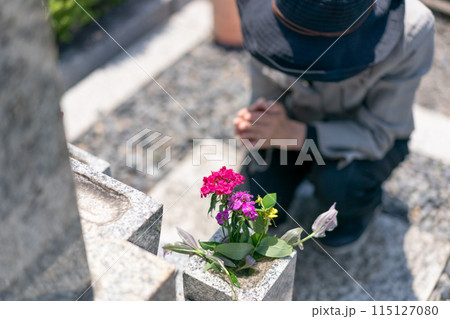 墓前で手を合わせて墓参りするシニア女性 115127080