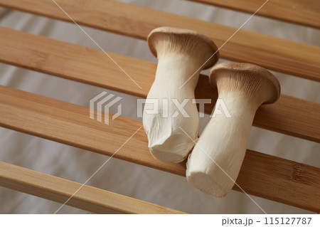 木の板に乗せられた二つのエリンギ 115127787