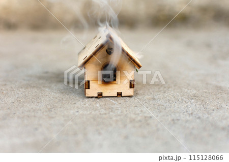 a toy wooden house is smoking. fire, disaster 115128066