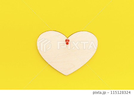 wooden heart on a yellow background pinned with a button wooden heart on a yellow background pinned with a button 115128324