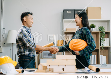 Construction team shake hands greeting start new project plan behind yellow helmet on desk in office center to consults about their building project.. 115128955