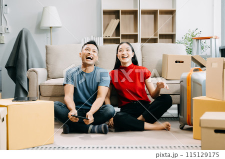 Young couple with big boxes moving into a new house, new apartment for couple, young asian man and woman helping to lift boxes on sofa for the new home. Young couple with big boxes moving into a new house, new apartment for couple, young asian man and woman helping to lift boxes on sofa for the new home. 115129175