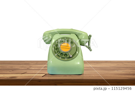 Green desk phone on a wooden table Isolated on a white background 115129456