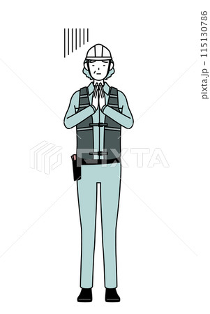 体の前で手を合わせて謝るヘルメットと作業着姿のシニア女性技師 体の前で手を合わせて謝るヘルメットと作業着姿のシニア女性技師 115130786