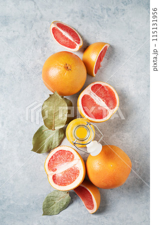 Flat lay of juicy red grapefruits and juice in a bottle on a blue background.  115131956