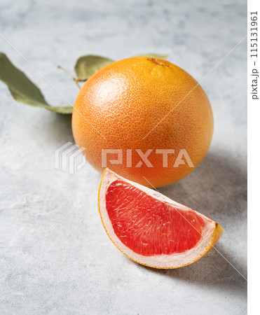 Juicy red grapefruit with slice and green leaf on a blue background close up.  115131961