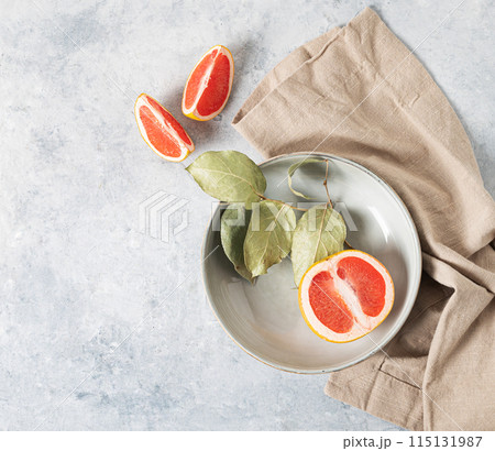 juicy red grapefruit in a plate and slices on a blue background with a light napkin.  juicy red grapefruit in a plate and slices on a blue background with a light napkin.  115131987