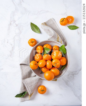 sweet and juicy tangerines in a ceramic bowl with linen napkin on a white marble background sweet and juicy tangerines in a ceramic bowl with linen napkin on a white marble background 115132024