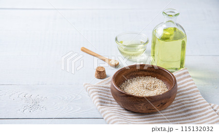 Natural vegetable oil from sesame seeds in a clear bottle on the wooden background. Natural vegetable oil from sesame seeds in a clear bottle on the wooden background. 115132032