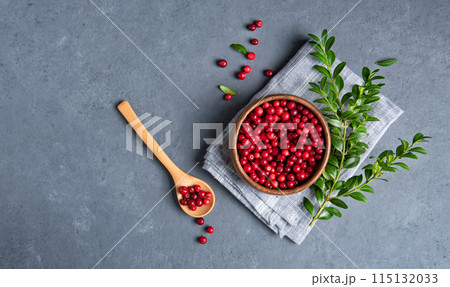 juicy forest lingonberry in a wooden bowl with spoon on dark gray table. Concept healthy food. juicy forest lingonberry in a wooden bowl with spoon on dark gray table. Concept healthy food. 115132033