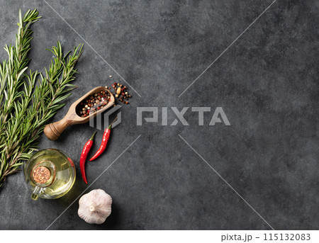 Spices and fresh herbs rosemary, garlic, pepper, chili pepper and oil on a dark gray background. Spices and fresh herbs rosemary, garlic, pepper, chili pepper and oil on a dark gray background. 115132083