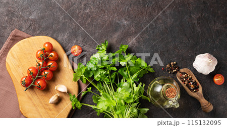 Spices and fresh herbs parsley, garlic, pepper, tomatoes and oil on a dark brown background.  115132095