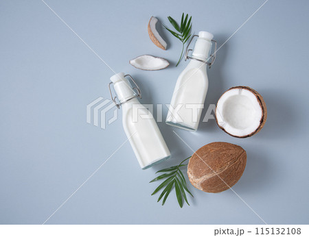 Vegan milk bottles, coconut slices and palm branch on blue background. Top  view and copy space 115132108