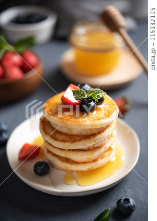 Homemade classic American pancakes in a stack with fresh berries and honey close-up Homemade classic American pancakes in a stack with fresh berries and honey close-up 115132115