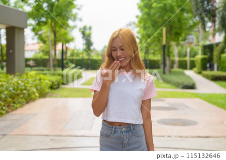 Portrait of beautiful Asian girl with blonde hair smiling and looking down while laughing 115132646