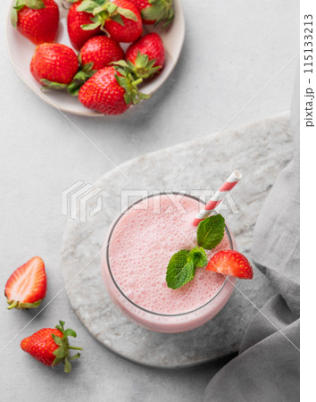 A glass of fresh strawberry smoothie with mint on a marble board on a light background  115133213
