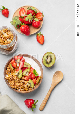 Natural yogurt with granola, kiwi and strawberries in a wooden bowl on a light background Natural yogurt with granola, kiwi and strawberries in a wooden bowl on a light background 115133242
