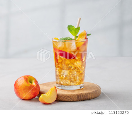 Refreshing peach iced mint tea. The concept of a healthy homemade cold summer drink in a tall glass Refreshing peach iced mint tea. The concept of a healthy homemade cold summer drink in a tall glass 115133270