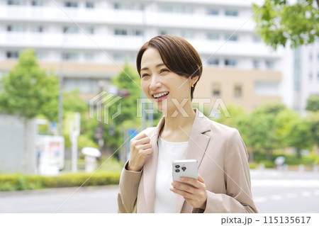 外でスマートフォンを使うビジネスウーマン 115135617