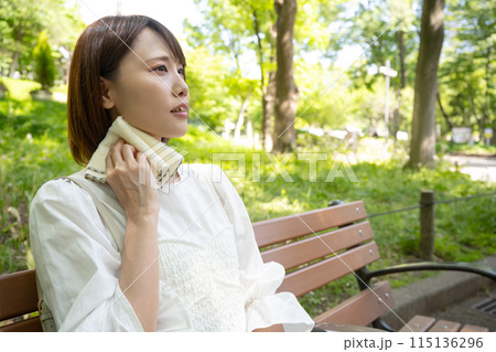 屋外のベンチに座って汗を拭く女性 屋外のベンチに座って汗を拭く女性 115136296