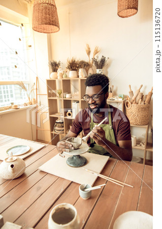 Smiling man painting pottery and looking enjoyed 115136720