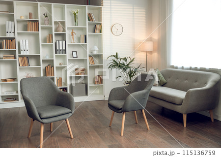 Psychologists office with cozy chairs sofa and shelves with books 115136759