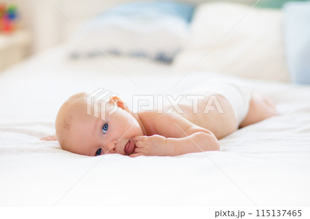 Little baby on white bed 115137465