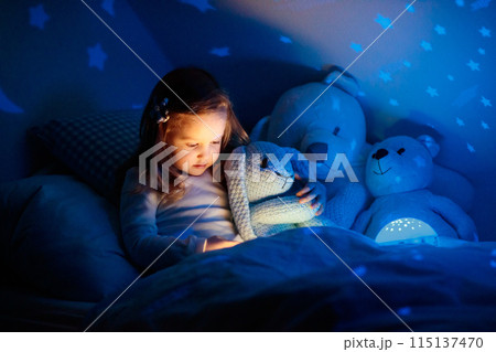 Little girl reading a book in bed Little girl reading a book in bed 115137470