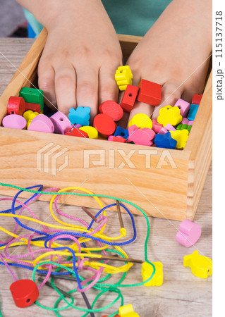 Preschooler playing thread and colorful beads used to making bracelets 115137718