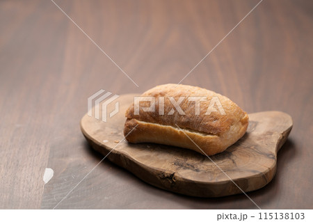 sliced ciabatta bun on wood board closeup 115138103